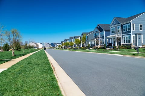 Row of modern detached houses along the road with lawn and sidewalk.